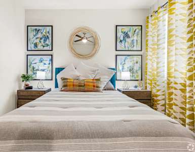 A bed with a striped comforter and a blue pillow is in the center of the image.